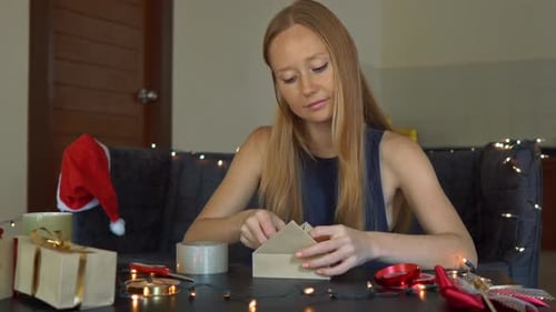Woman Wrapping Christmas Gift at Home