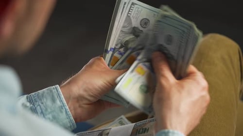 Person Counts Stacks of One Hundred Dollar Bills