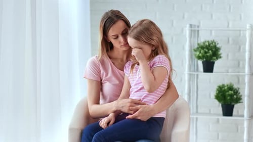 Fürsorgliche junge Mutter tröstet kleine süße weinende Tochter, die Liebe umarmt