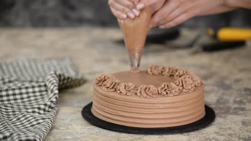 Woman Decorating a Chocolate Cake with Frosting