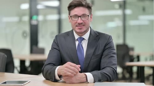 Positive Middle Aged Businessman Doing Video Chat in Office
