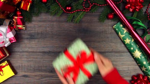 Festive Hands Placing Christmas Gift on Wooden Surface