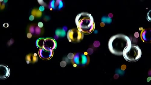 Bulles de savon moyennes en rotation. Ralenti. Fond noir.