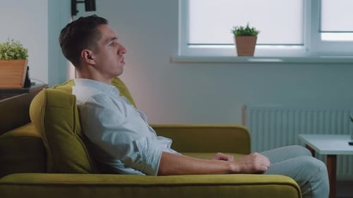 Tired Business Man Resting After Work on the Couch at Home. Sad Male Suffering From Headache Sitting