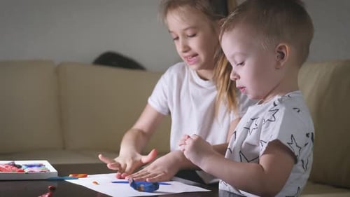 Girl and Boy Play With Clay at Table