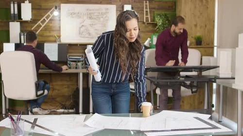 Female Architect Arriving at the Office Holding a Coffee and a Blueprint