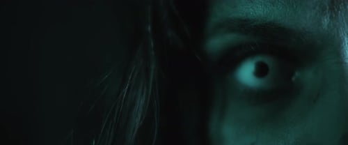 Terrifying creepy zombie woman, close up of white eye opening. Scary look.