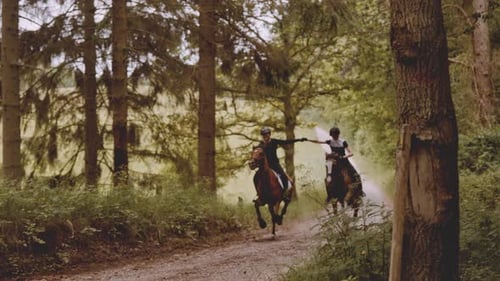 Zwei Reiterinnen halten die Hände hoch, während sie auf braunen Pferden reiten