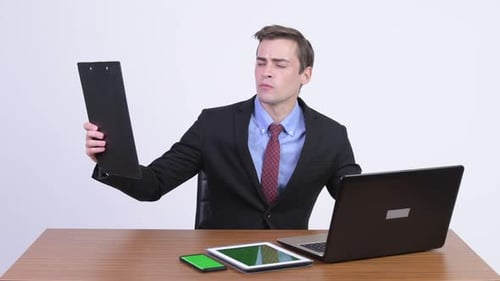 Young Handsome Businessman Multi-tasking Work Against Wooden Table