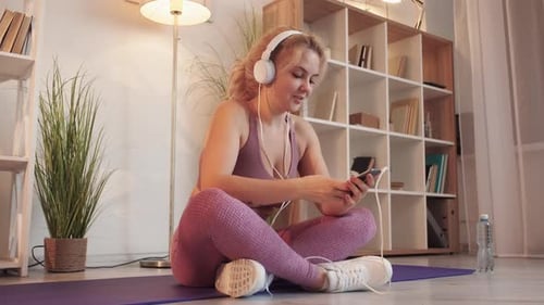 Woman Listens to Music Before Workout at Home