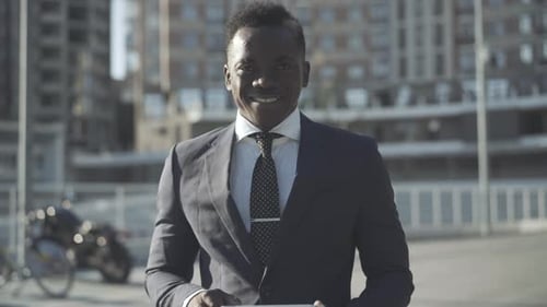 Portrait of Confident Handsome African American Businessman Posing in Sunlight on City Street