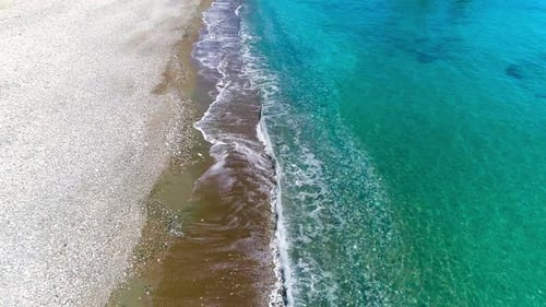 Aerial Top View of Waves Crash on the Beach in a Blue Ocean