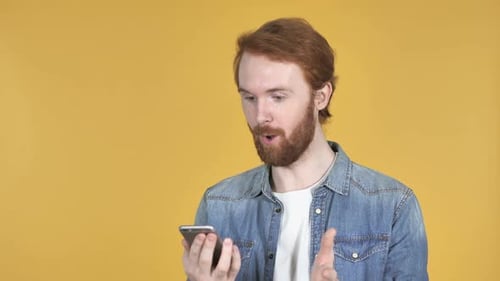 Auburn-haired Adult Using Smartphone on Yellow Backdrop