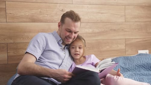 Father and Daughter Reading a Book Together Indoors