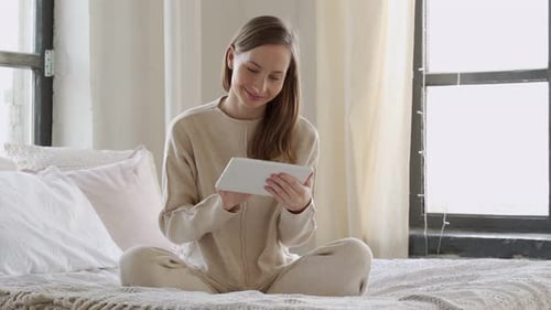 Woman Using Tablet Device While Relaxing on Bed