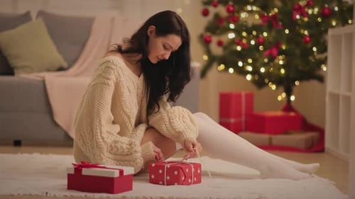 Woman Ties Christmas Gift Ribbon at Home