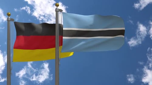 German and Botswana National Flags Waving Against Blue Sky