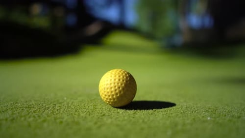 Mini Golf Yellow Ball with a Bat near the Hole at Sunset