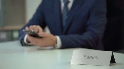 Banker Using Smartphone at Desk in Office