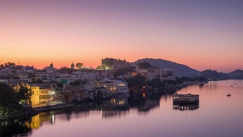 Udaipur cityscape at sunrise. The majestic city palace and boats riding on Lake Pichola