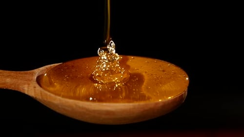 Thick Honey Dipping Over the Spoon, on Black, Close Up, Macro, Slow Motion