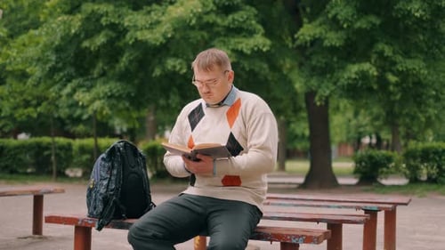 A Funny Nerdy Man Is Reading Book Outdoor. A Bookworm Loser with Glasses Is Preparing To Exam.