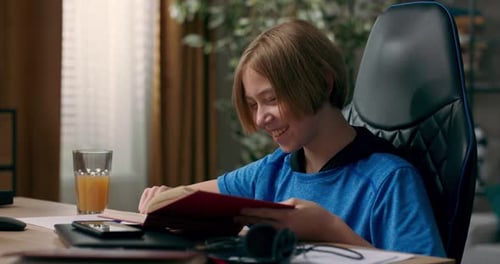 An Ambitious Teenager Sits in Room in the Morning Holds a Book a Notebook in Hands