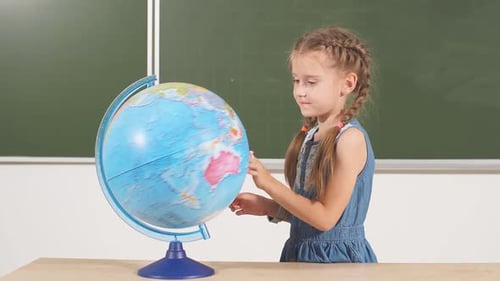 Schulmädchen mit Globus im Klassenzimmer Kreidetafel auf Hintergrund