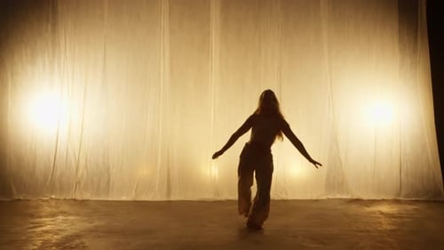 Silhouette of a Professional Dancer Performing in Studio in Soft Warm Lighting