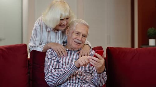 Loving Senior Couple Using Smartphone at Home