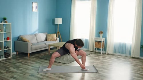 Athletic Man Stretching Legs on Yoga Mat