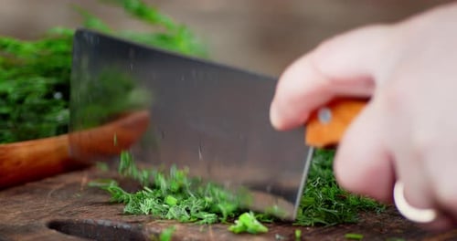 Man's Hand with a Large Knife Cut the Fresh Dill.