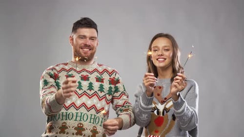 Couple in Christmas Sweaters Holding Sparklers