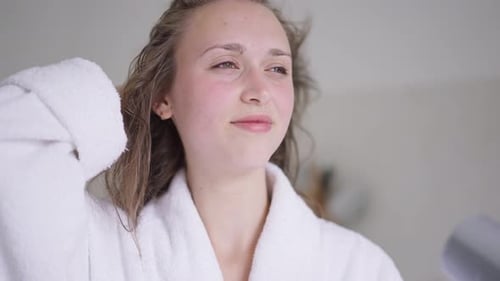 Woman Dries Hair with Hairdryer in Robe