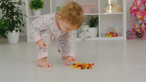 Child Playing with Gummy Candies on Floor