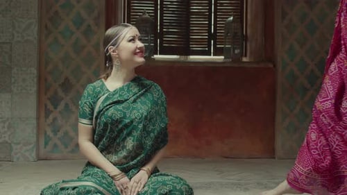 Two Women in Saris Interact Indoors