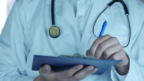 Doctor Writing on Clipboard in Clinic Setting