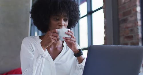 Happy african american woman sitting in cafe drinking cup of coffee and smiling