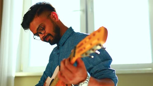 Man Plays Guitar in Brightly Lit Room