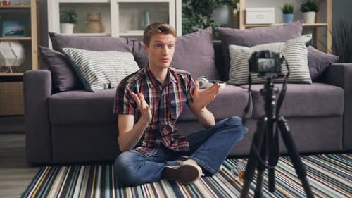 Fröhlicher junger Mann Beliebter Vlogger nimmt Video für seinen Online-Blog auf Sprechen und Gestikulieren