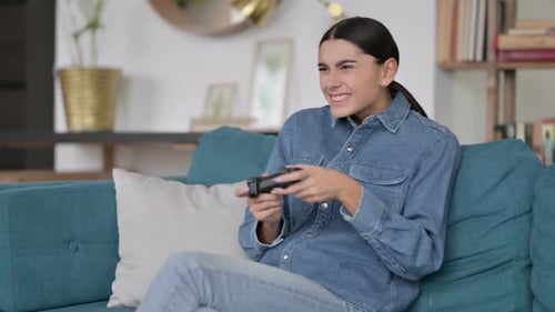 Latin Woman Having Loss on Video Game on Sofa