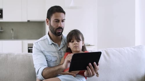 Father and Child Using Tablet Together on Couch
