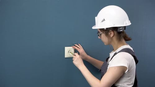 An Electrician Repairs an Outlet in the House