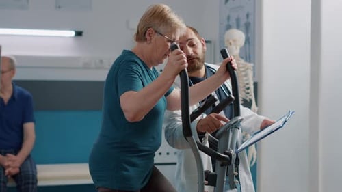 Senior Woman Using Elliptical with Doctor Guidance