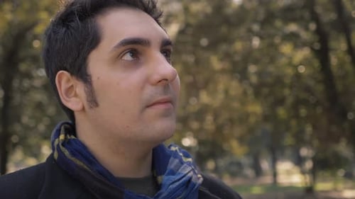 happy relaxed young man in the park looking up-slow motion