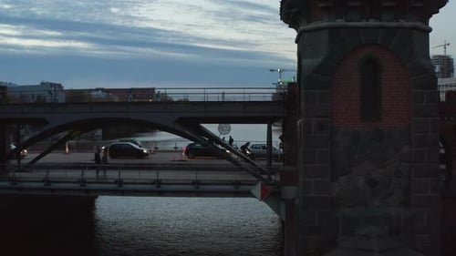 Bikers and Car Traffic on Berlin Oberbaum Bridge Old Famous Building Over Spree River in Evening