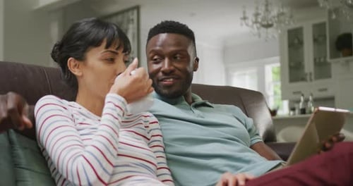 Couple Relaxing on Couch Using Tablet at Home