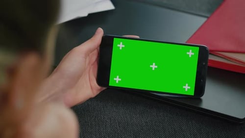 Woman sitting on a sofa with smart phone in horizontal mode.