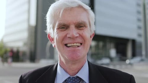 Senior business man looking at camera outside office buildings in background - Entrepreneur concept