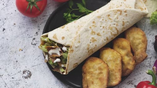 Traditioneller türkischer Döner-Kebab im Wrap, serviert mit frischen Zutaten und frittierten Knödeln